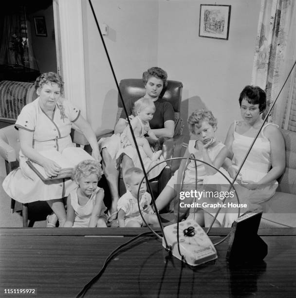 Woman and her family watching television with a Rembrandt TV antenna which she has set up, circa 1955.