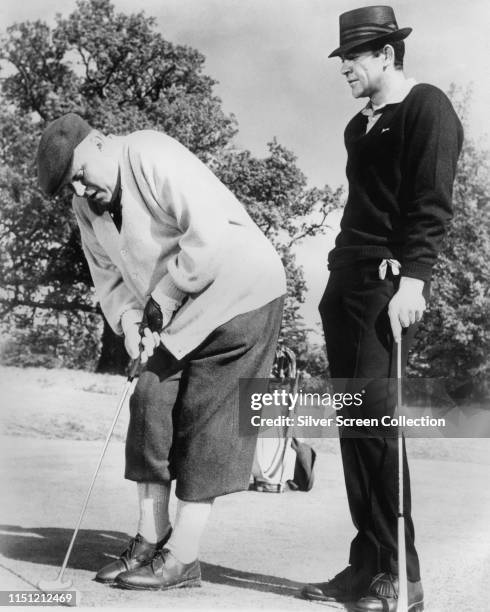 Actors Sean Connery as James Bond and Gert Frobe as Goldfinger in a golf scene from the film 'Goldfinger', 1964.