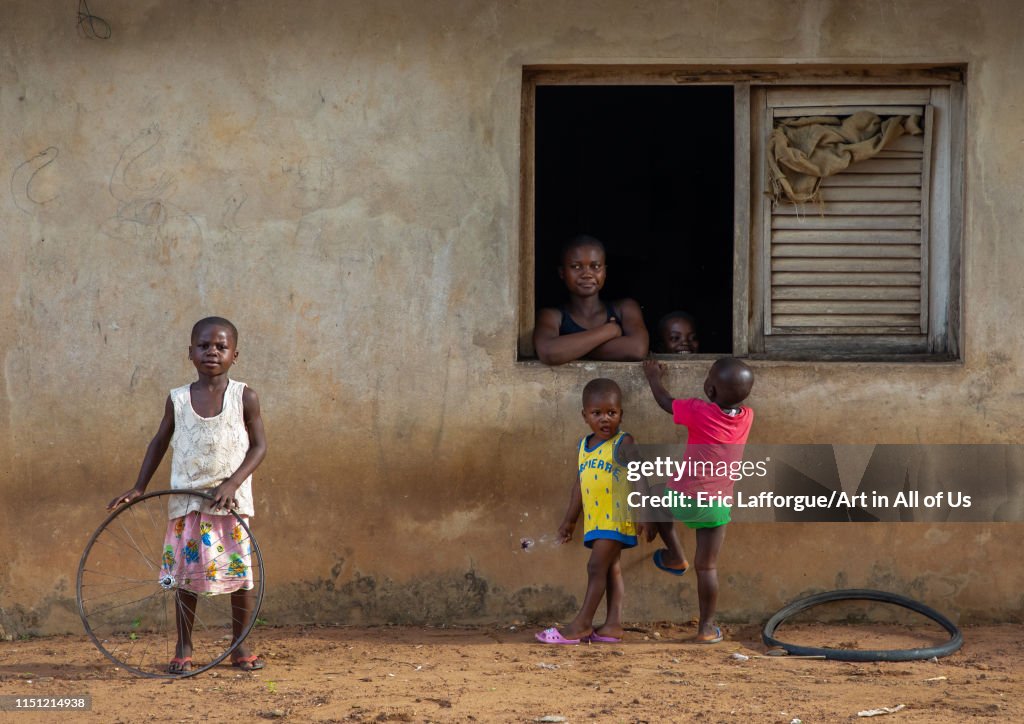 African mother looking thru her window house her children playing, Région des Lacs, Bomizanbo, Ivory Coast...