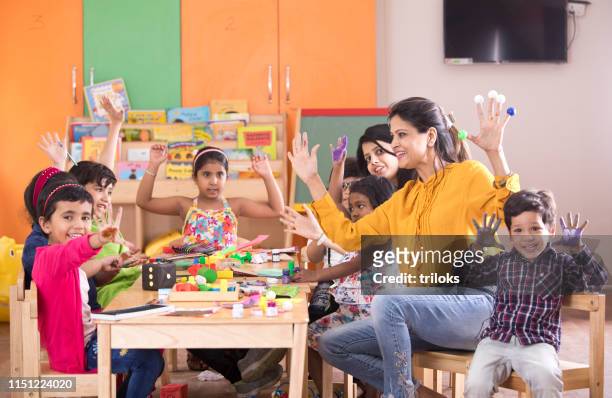profesora de preescolar con pintura de dedos en clase - indian child fotografías e imágenes de stock