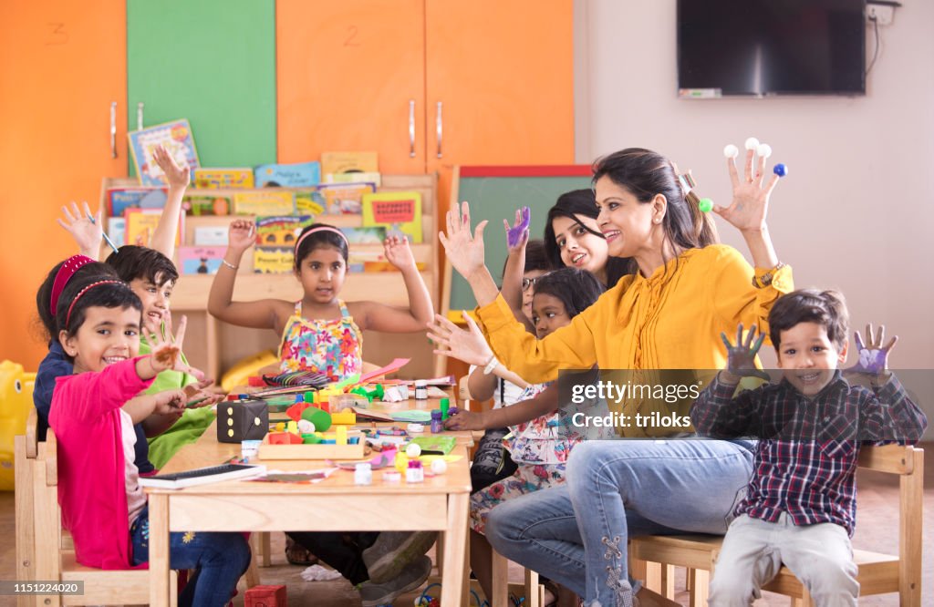 Teacher with preschoolers finger painting at class
