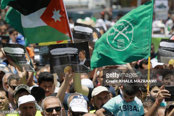 Flag of Jordan and the Muslim Brotherhood are waved next to a sign showing Egypt's late ousted president Mohamed Morsi, with captions in Arabic...