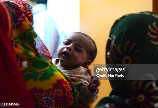 An Indian local woman of Mushahari village stand in a queue with her child to take appointment of doctor for AES checkup at community health centre ,...