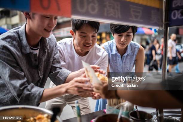 drie mensen zijn het bestellen van voedsel op een straat voedsel teller. - taiwanese ethnicity stockfoto's en -beelden