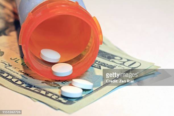 prescription pill medication spilling out of container on american twenty dollar bills - prescription drug costs stock pictures, royalty-free photos & images