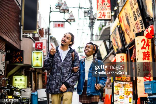 young couple on vacation in tokyo exploring city streets - japan tourism stock pictures, royalty-free photos & images