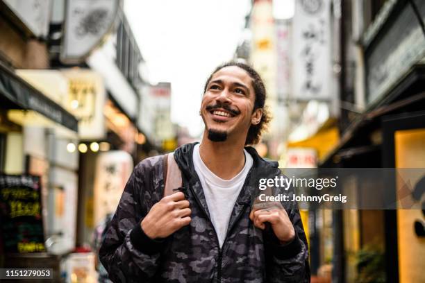 vrolijke jonge man met geitee opzoeken in de city street - sabbatical stockfoto's en -beelden