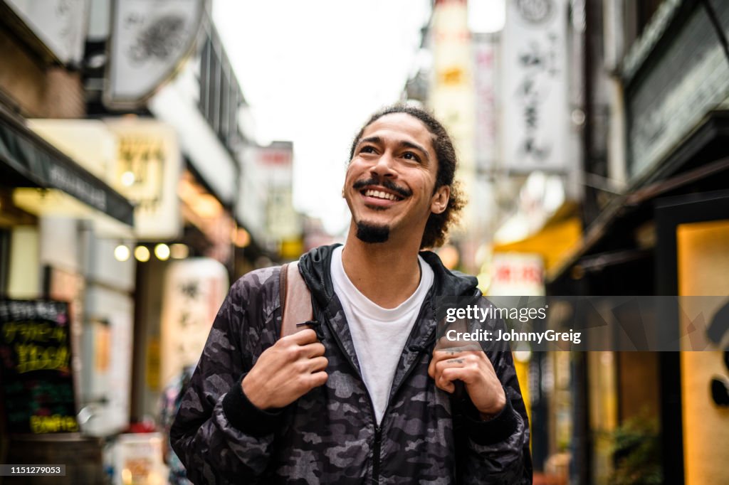 Cheerful young man with goatee looking up in city street