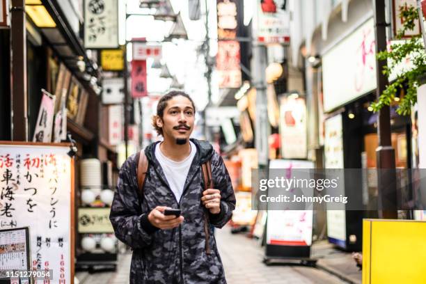 junger mann in stadtstraße mit smartphone - foreign language stock-fotos und bilder