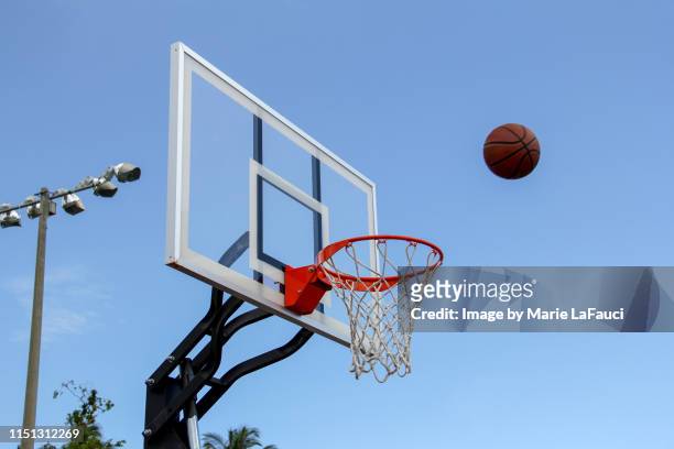 basketball in midair near basketball hoop outdoors - basketball hoop stockfoto's en -beelden