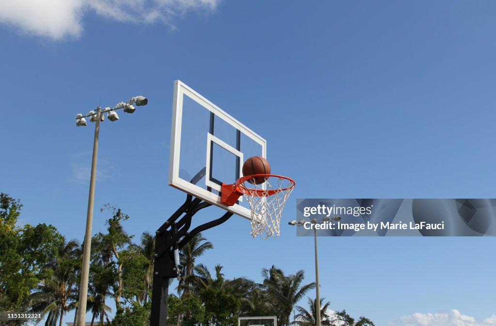 Basketball inside rim of basketball hoop outdoors