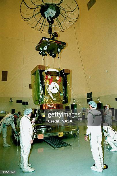In the Payload Hazardous Servicing Facility, workers help guide the overhead crane lifting the Stardust spacecraft. Stardust is being moved in order...
