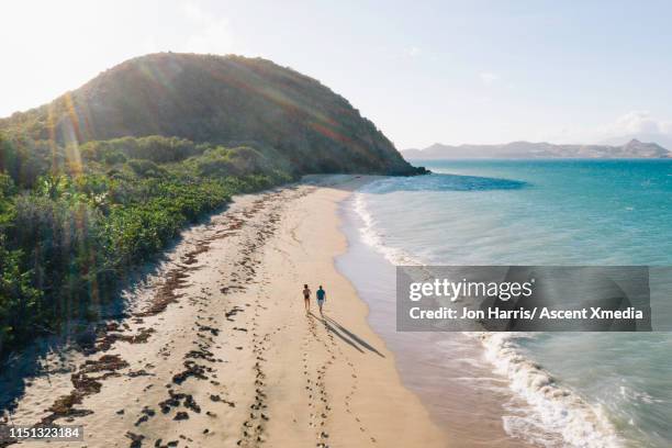 aerial view of couple walking along beach - caraïbische zee stockfoto's en -beelden