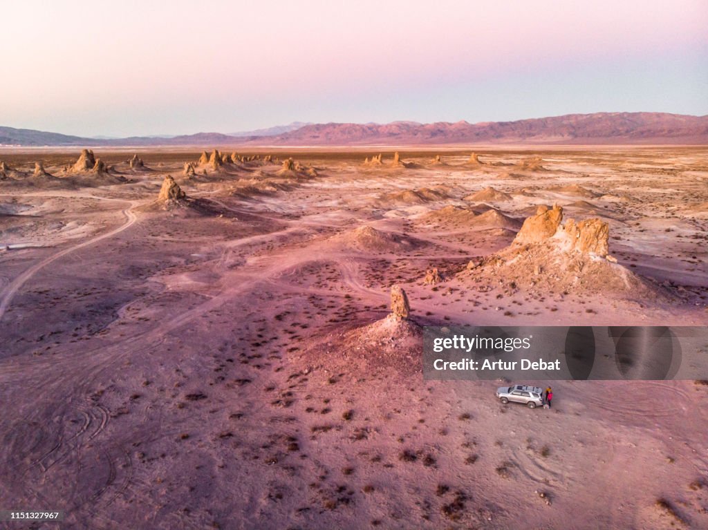 Drone view of adventurous people traveling by car in the California desert formations.