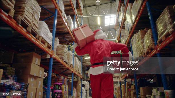 kerstmis in een pakhuis. santa claus dragen kerstcadeaus - kerstmuts stockfoto's en -beelden