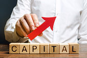 Man holds red arrow up above word Capital. Increase investment and foreign capital in the national economy. Improve business climate and increase attractiveness. Growth and stability of the economy