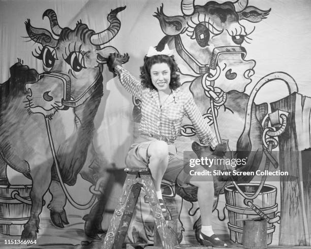 American actress and comedian Judy Canova in front of a mural of cows, circa 1945.