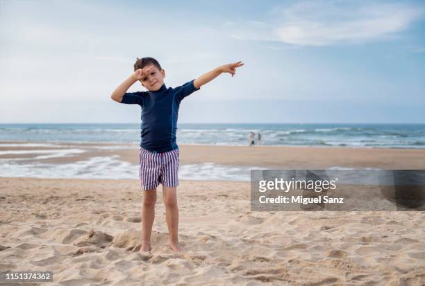 boy with his wetsuit on the beach - solo niños playa stock-fotos und bilder