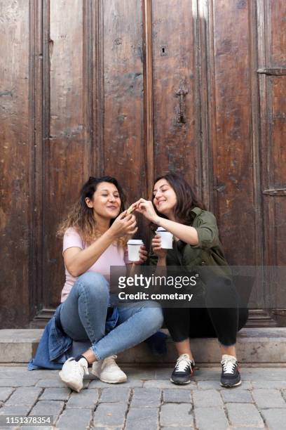 jonge vrouwen delen van cookies met koffie - koffiekoek stockfoto's en -beelden