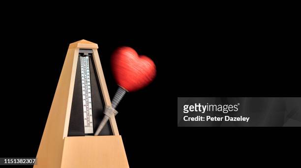 heart on moving metronome - metronome stock pictures, royalty-free photos & images