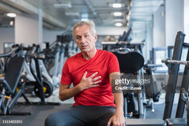 elderly man feeling chest pain at gym - man with chest pain stock pictures, royalty-free photos & images