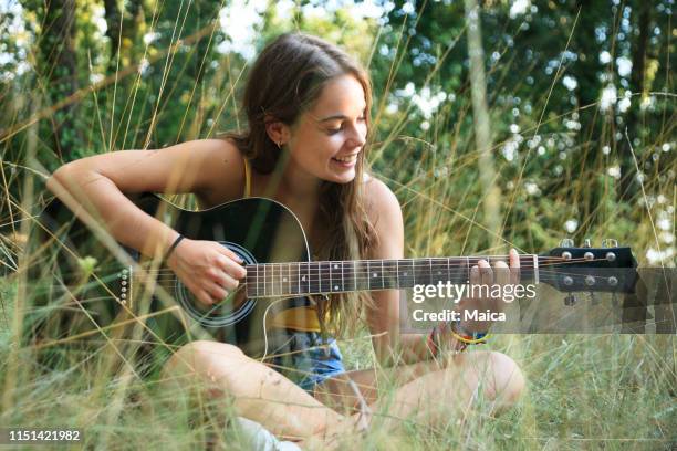 teen mädchen spielen gitarre - saiteninstrument spielen stock-fotos und bilder
