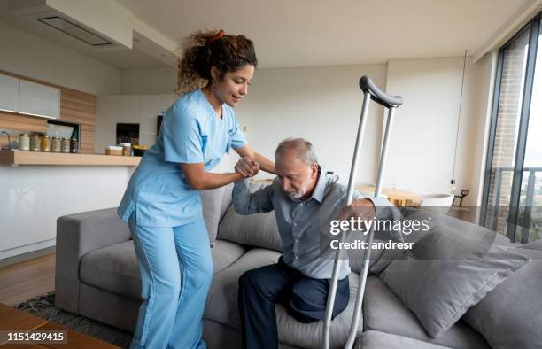 home caregiver helping a disabled senior man to stand up - diabetic amputation stock pictures, royalty-free photos & images