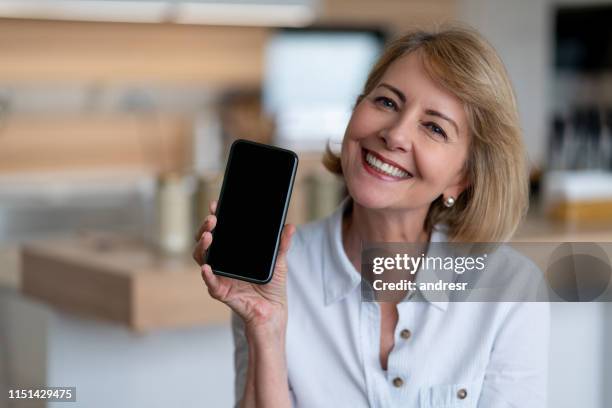 very happy senior woman at home using app on her cell phone - showing mobile stock pictures, royalty-free photos & images