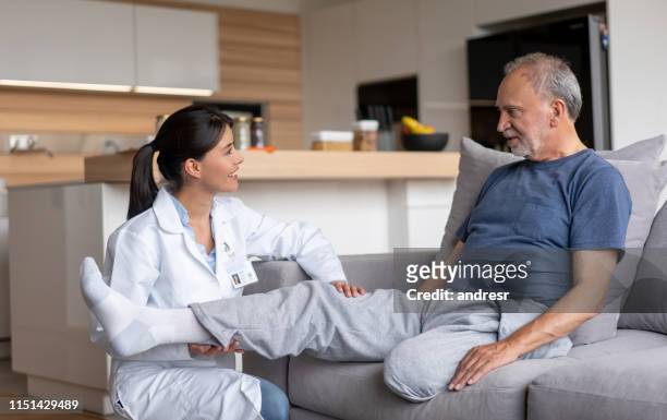 doctor making visiting a disabled senior patient at home - amputado imagens e fotografias de stock