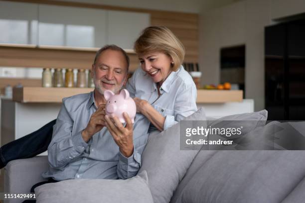 piggybank で彼らの貯蓄を保持しているシニアカップル - couple saving piggy bank ストックフォトと画像
