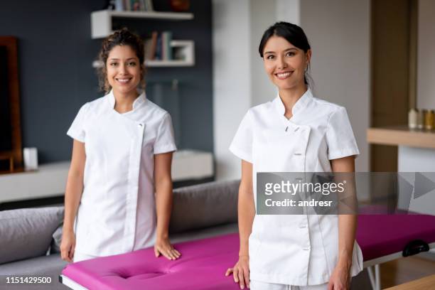 equipe dos massagistas que olham felizes na casa de um cliente - terapeuta de beleza - fotografias e filmes do acervo