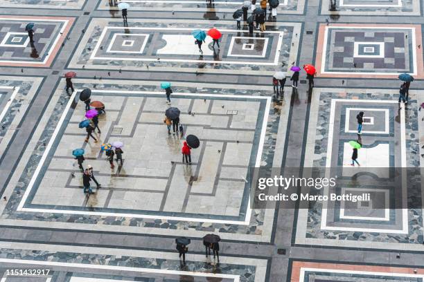 people with umbrellas walking in piazza del duomo (cathedral square), milan - daily life at duomo square milan stockfoto's en -beelden