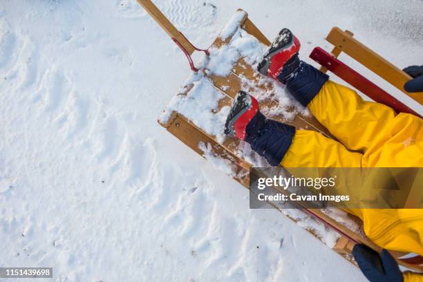 high angle of toddler sitting in wooden sled during winter. - sneeuwschoen stockfoto's en -beelden