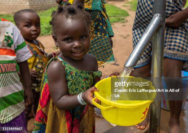 African children collecting water from a well with a pump, Bafing, Yo, Ivory Coast on May 5, 2019 in Yo, Ivory Coast.