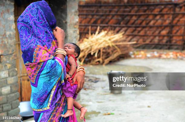 An indian woman stands with her child, outside of her home in Harvansh pur village, vaishali District , some 35 kms from MuzaffarPur , Bihar on June...