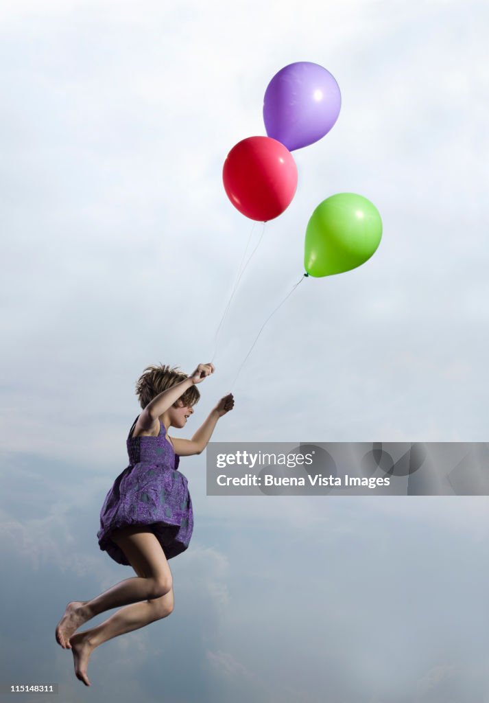 Little girl carried in air by balloons