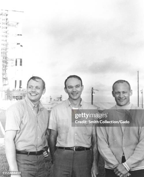 S Apollo 11 flight crew, Neil A Armstrong, Michael Collins, and Buzz Aldrin, stand near the Apollo/Saturn V at Kennedy Space Center in Florida, July...