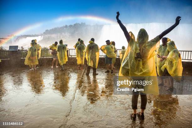 tourists wear ponchos to protect from the wet mist in niagara falls ontario canada - horseshoe falls niagara falls stock pictures, royalty-free photos & images