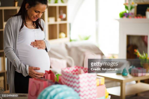 vrouw holding zwangere buik op baby shower partij - babyshower stockfoto's en -beelden