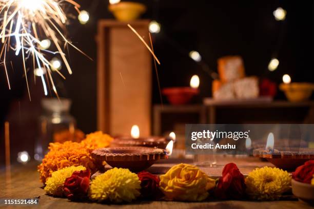 diwali celebrations with traditional clay oil diyas or lamps on wooden background with flower arrangement and fire crackers - india diwali lights stock-fotos und bilder