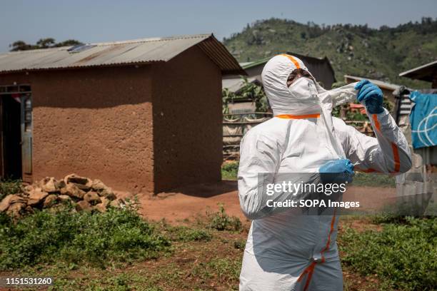 World Health Organization worker Belinda Landu changes her protective outfit after decontaminating the house of a pastor who has just tested positive...