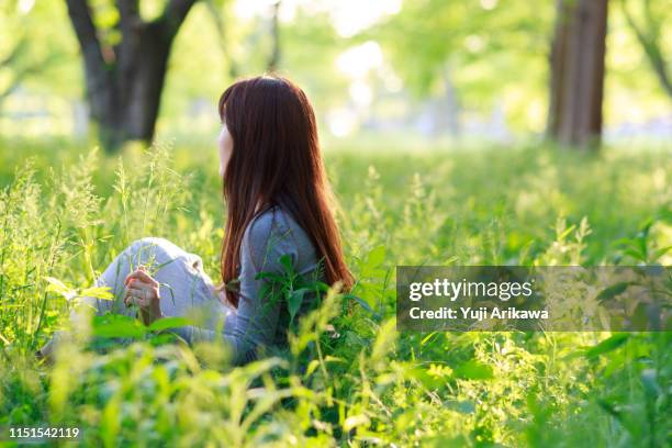 a woman sitting in the green grass - forest bathing stock pictures, royalty-free photos & images