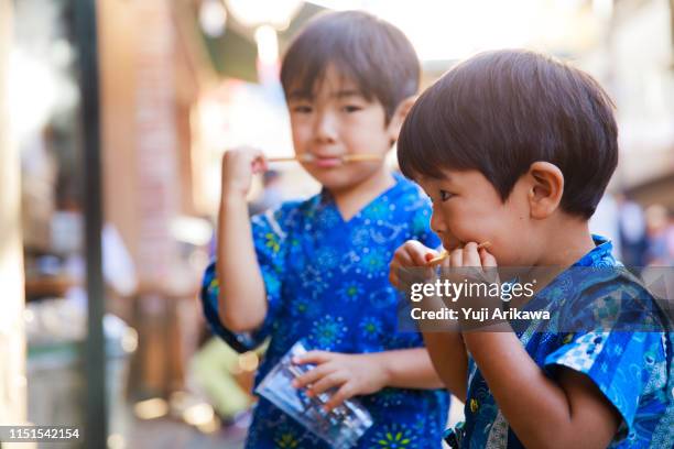 boys eating eating dumplings at a festival - 祭り ストックフォトと画像