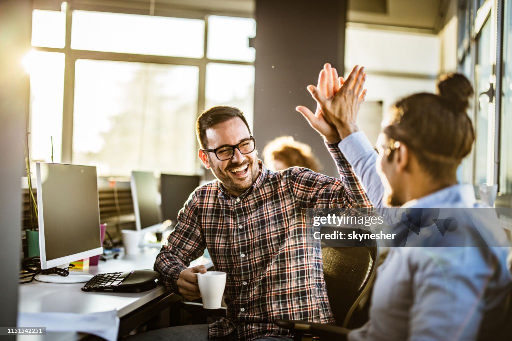 Gelukkige mannelijke programmeurs geven elkaar High-Five in het kantoor.