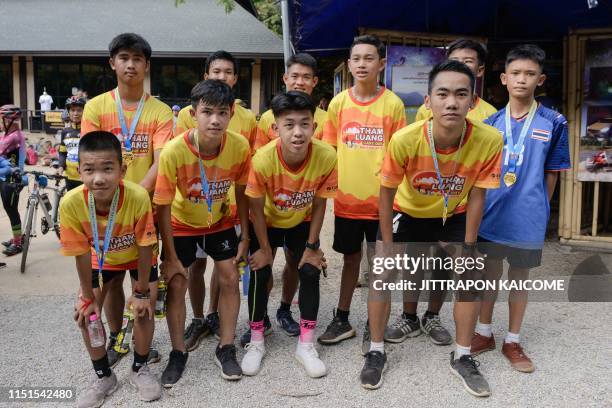 Members of the "Wild Boars" football team and their coach pose before participating in a marathon at the visitor centre for the Tham Luang cave,...
