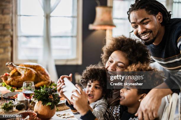 happy african american family taking a selfie during thanksgiving lunch. - african-american-family-thanksgiving stock pictures, royalty-free photos & images
