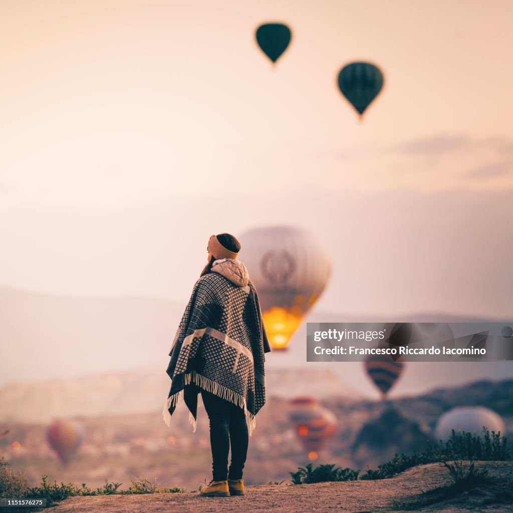 Tourist woman admiring hot air balloons rising in Cappadocia