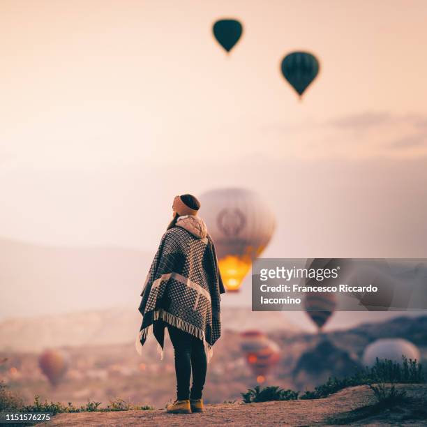 tourist woman admiring hot air balloons rising in cappadocia - cappadocia hot air balloon stock pictures, royalty-free photos & images