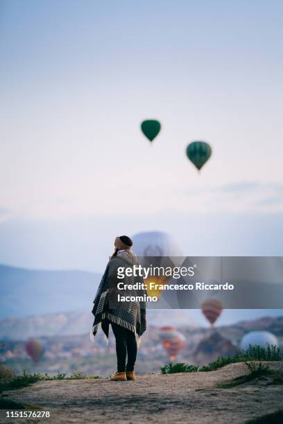 tourist woman admiring hot air balloons rising in cappadocia - hot air balloon ride stock-fotos und bilder