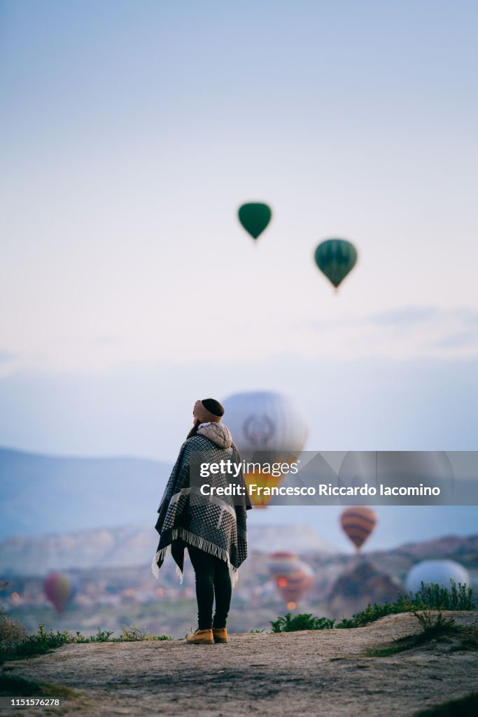 Tourist woman admiring hot air balloons rising in Cappadocia
